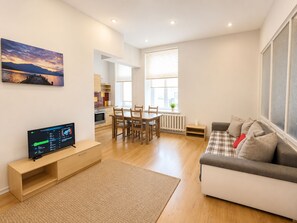 Una sala de estar moderna con un sofá, un televisor y un comedor con sillas y una mesa.