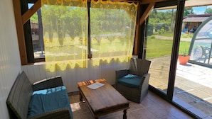 Une pièce avec une table en bois, deux chaises en osier et une grande fenêtre ornée de rideaux jaunes.