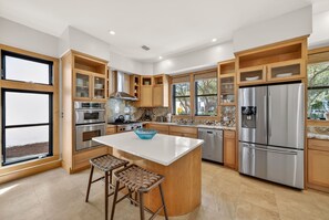 Una cocina moderna con armarios de madera, electrodomésticos de acero inoxidable y una isla grande con taburetes de bar.
