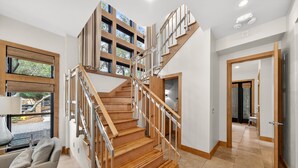 Un interior moderno con una escalera de madera, un sofá y un ventanal con vistas.
