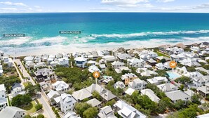 A coastal residential area with beach access, featuring houses with varied roof styles and a clear view of the ocean. - In Rosemary Beach, steps to beach / Coquina pool, Pet-Friendly, Corner Park (Rosemary Beach)