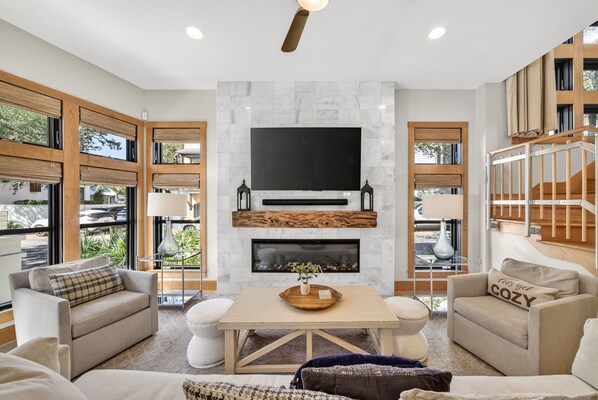 A modern living room with a large TV, fireplace, and comfortable seating.