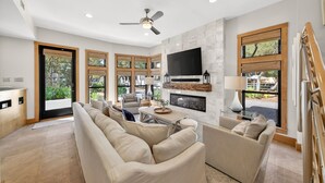 Un salón amplio con chimenea, asientos cómodos y ventanas grandes.