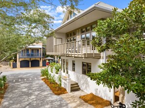 A two-story house with a balcony, a garage, and a well-maintained garden.