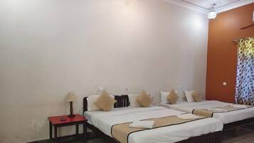 A hotel room with two beds, a nightstand, a lamp, and a patterned curtain.
