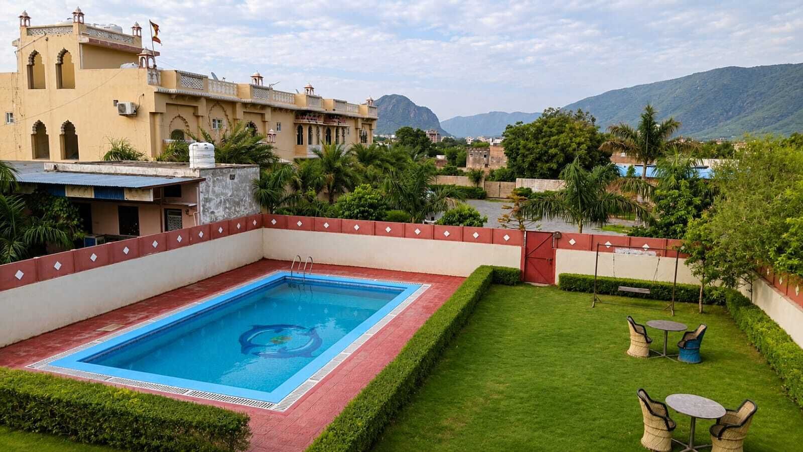 Una piscina con borde rojo, rodeada por un césped cuidado y algunas sillas.