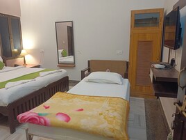 Una camera d'albergo con due letti, un armadio in legno, uno specchio e un televisore.