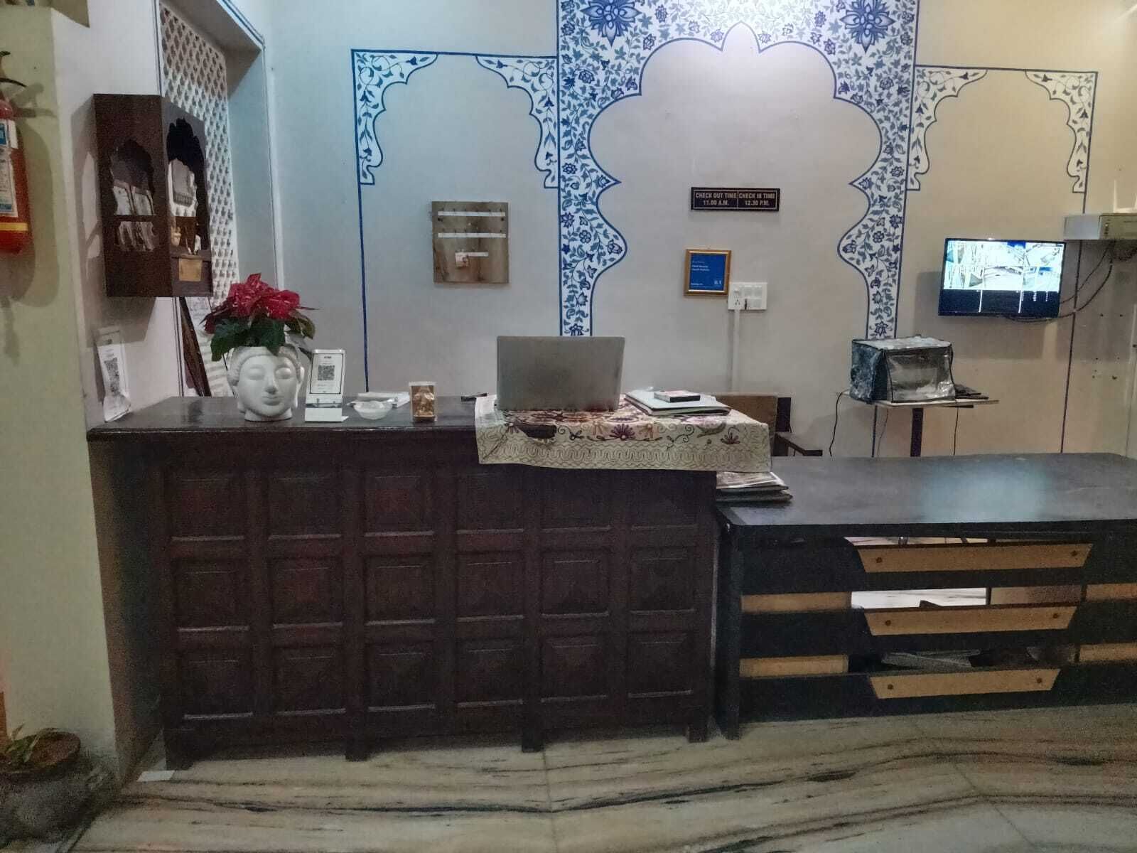 A reception area with a desk, a laptop, a small TV, and a decorative wall.
