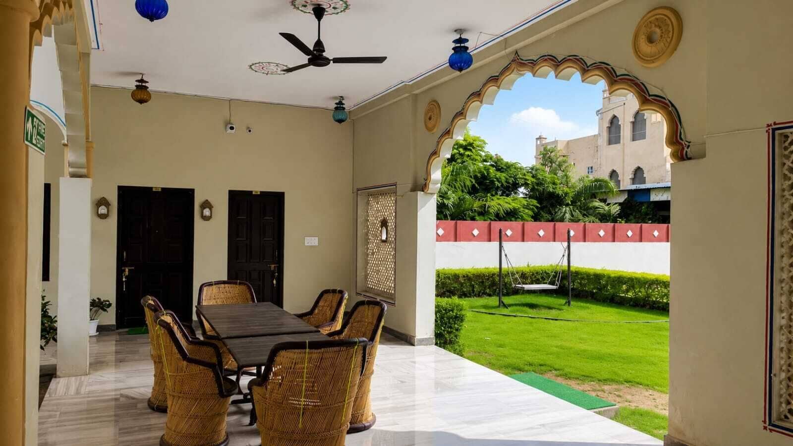 A room with a dining table and chairs, a ceiling fan, and a view of a garden.