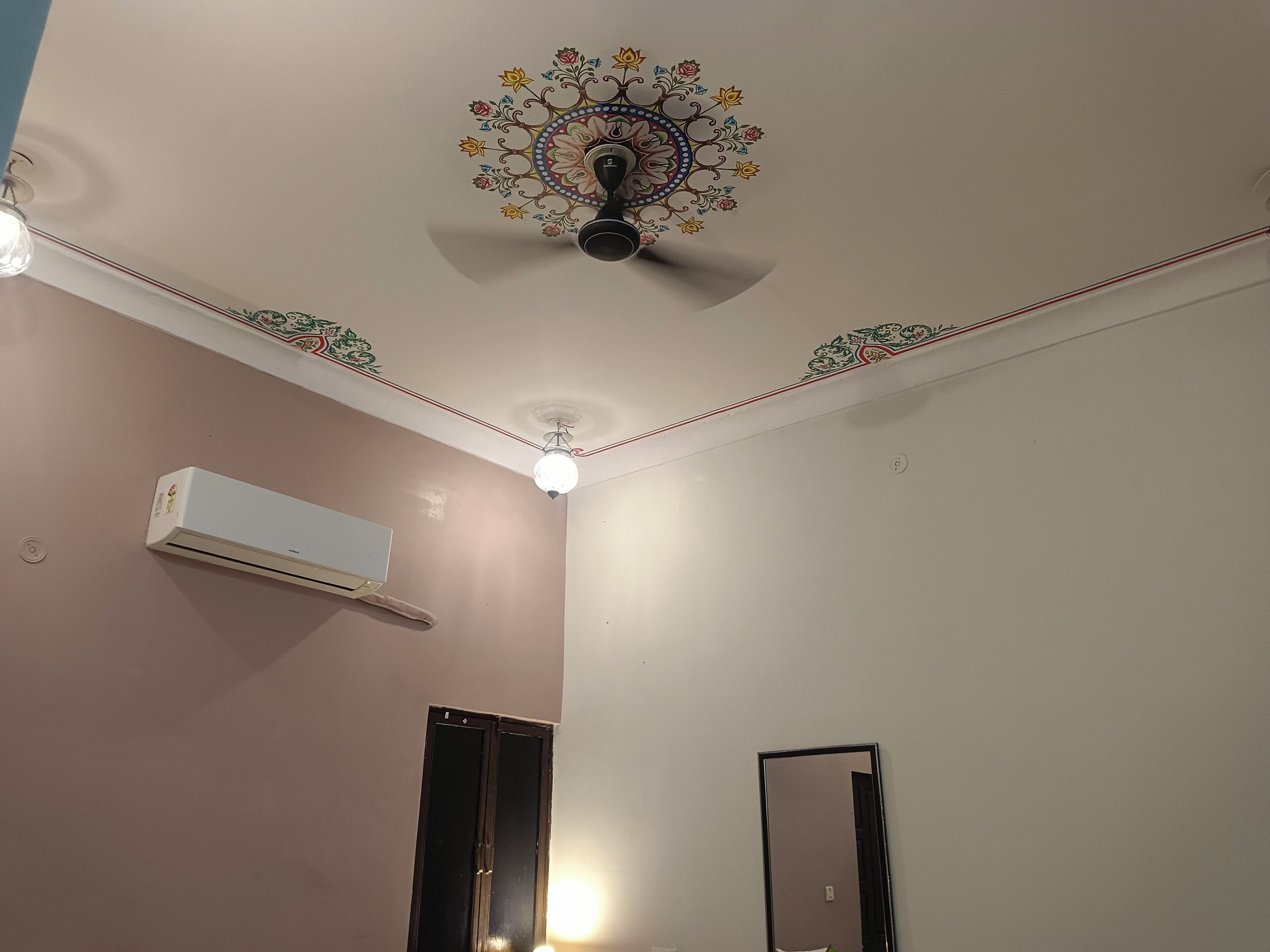 Una stanza con ventilatore a soffitto, condizionatore d'aria, una porta e uno specchio.
