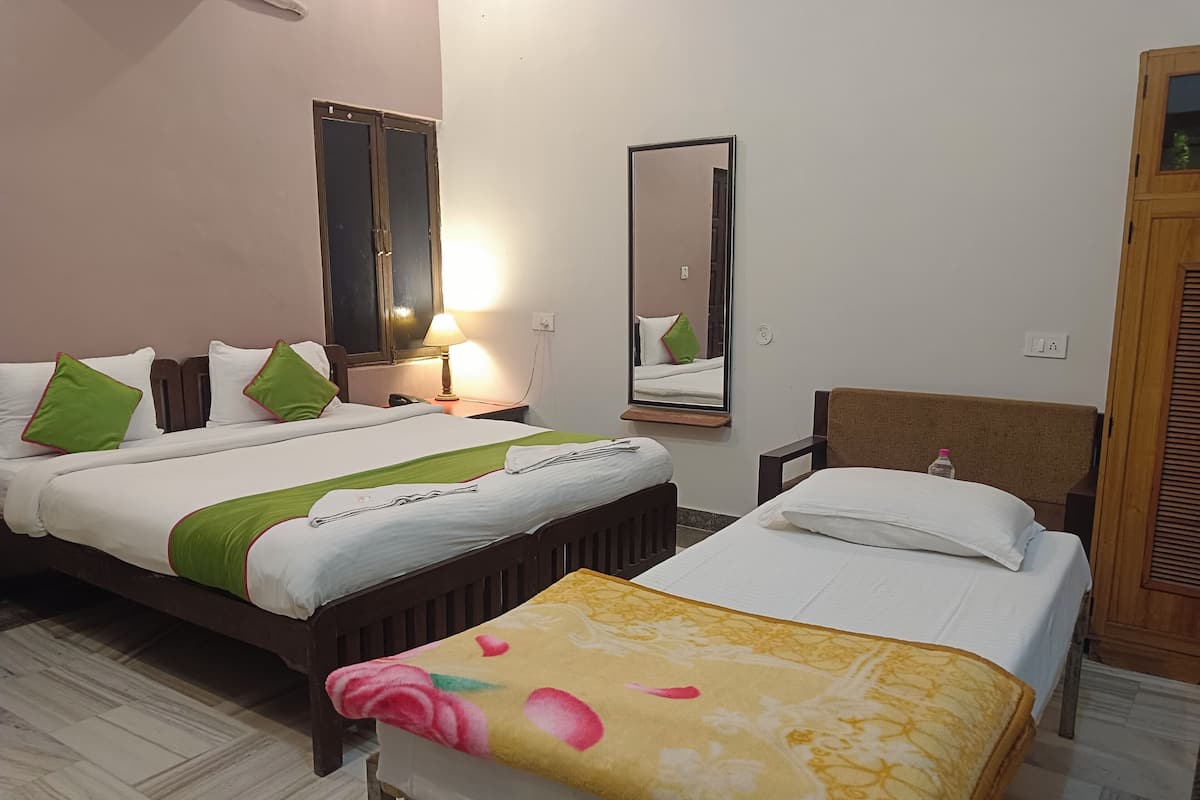 A hotel room with two beds, a mirror, a lamp, and a wooden headboard.