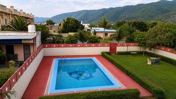 A rectangular swimming pool with a blue interior, surrounded by a red border and a white wall.