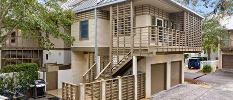 A two-story residential building with a balcony, a garage, and a bicycle parked outside.