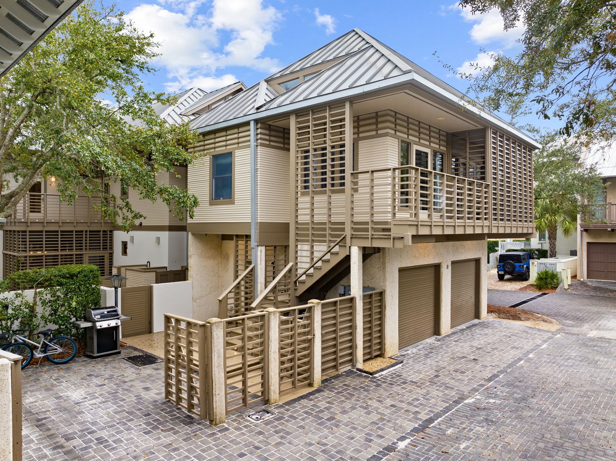 Een woonhuis met twee verdiepingen, een balkon, een garage en een fiets geparkeerd voor.