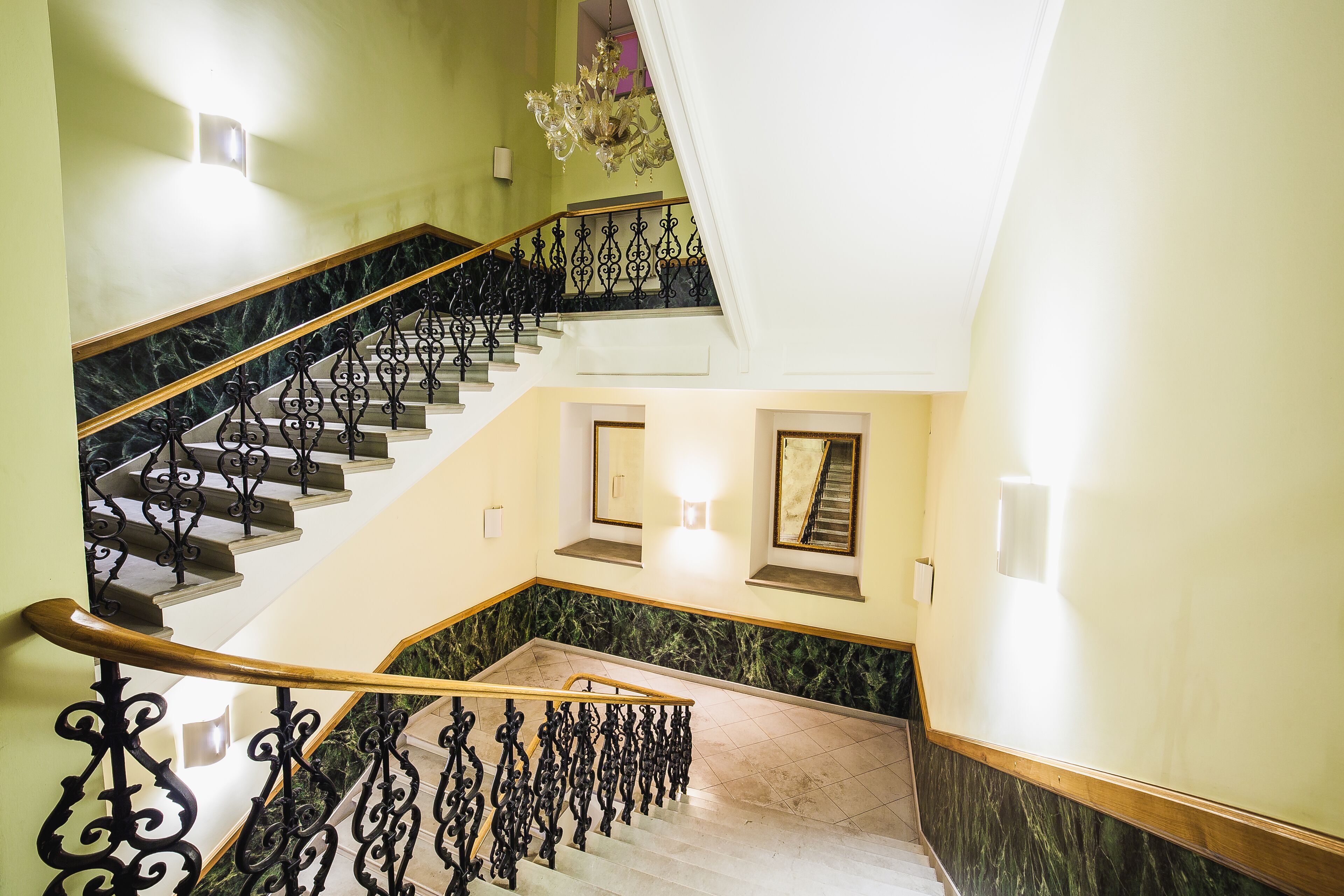 A grand staircase with ornate black railings and marble steps, leading to an upper floor.