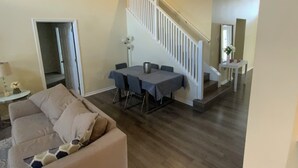 Ein geräumiges Wohnzimmer mit hohen Decken, einer Treppe und einem Essbereich.