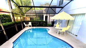 Ein Schwimmbecken mit Glasabdeckung, umgeben von Stühlen und einem Sonnenschirm.