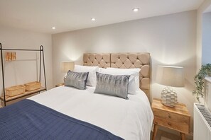 Relax in this serene bedroom with a large bed, two bedside tables, and a nightstand with a drawer.