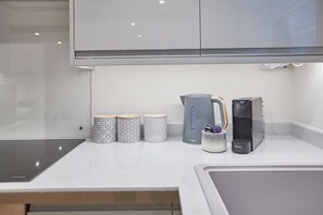 Effortlessly cook and prepare meals in this modern kitchen, featuring an induction cooktop, kettle, and coffee maker.