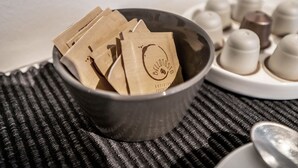 A bowl filled with brown paper bags labeled "Bellotosto" on a textured surface. - Emilia Suite Essence (Modena)