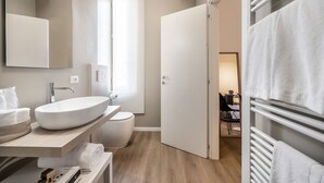 A modern bathroom with a large sink, toilet, and a walk-in shower. - Emilia Suite Essence (Modena)