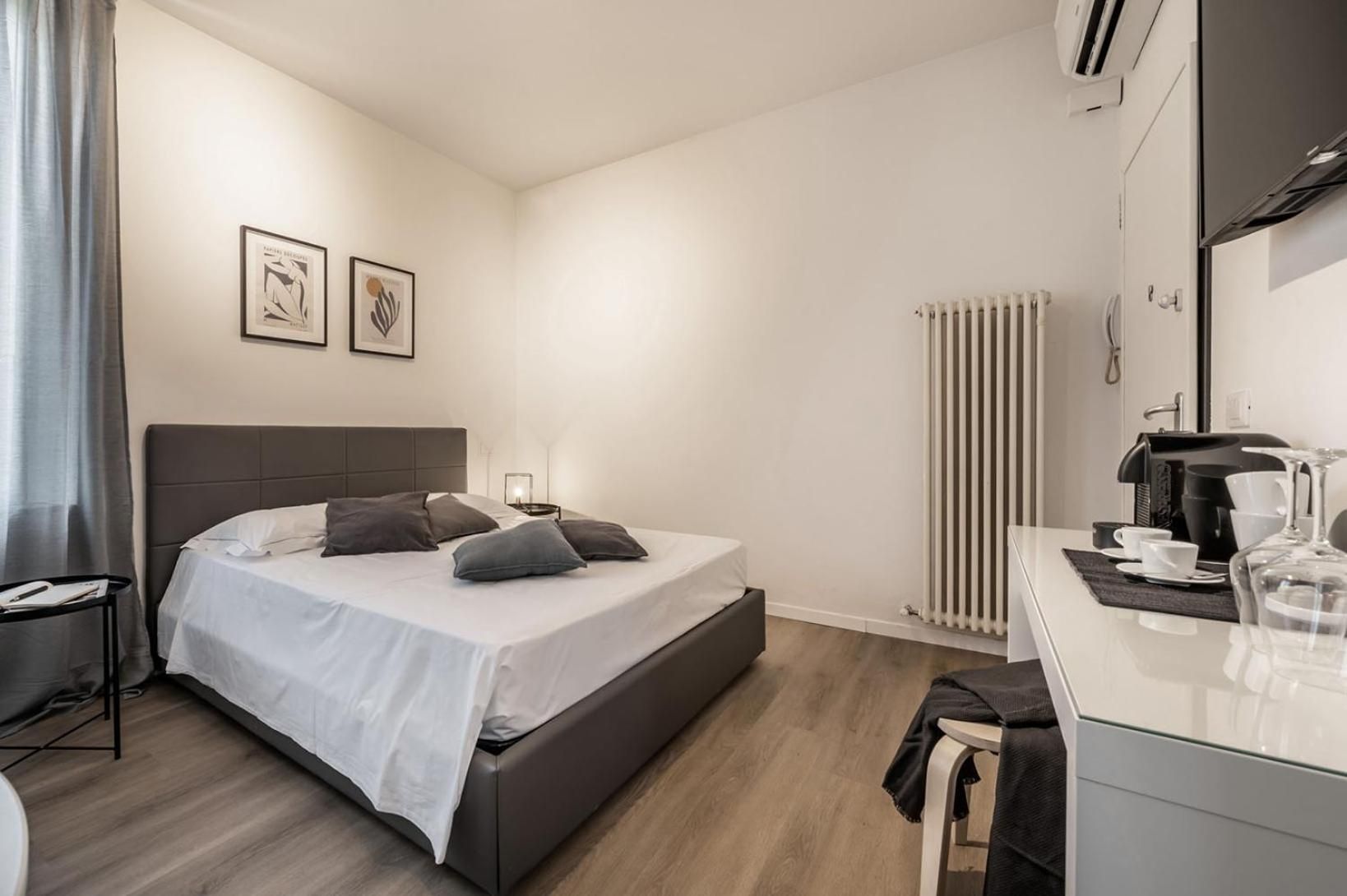 A modern hotel room with a bed, bedside table, and a coffee station.