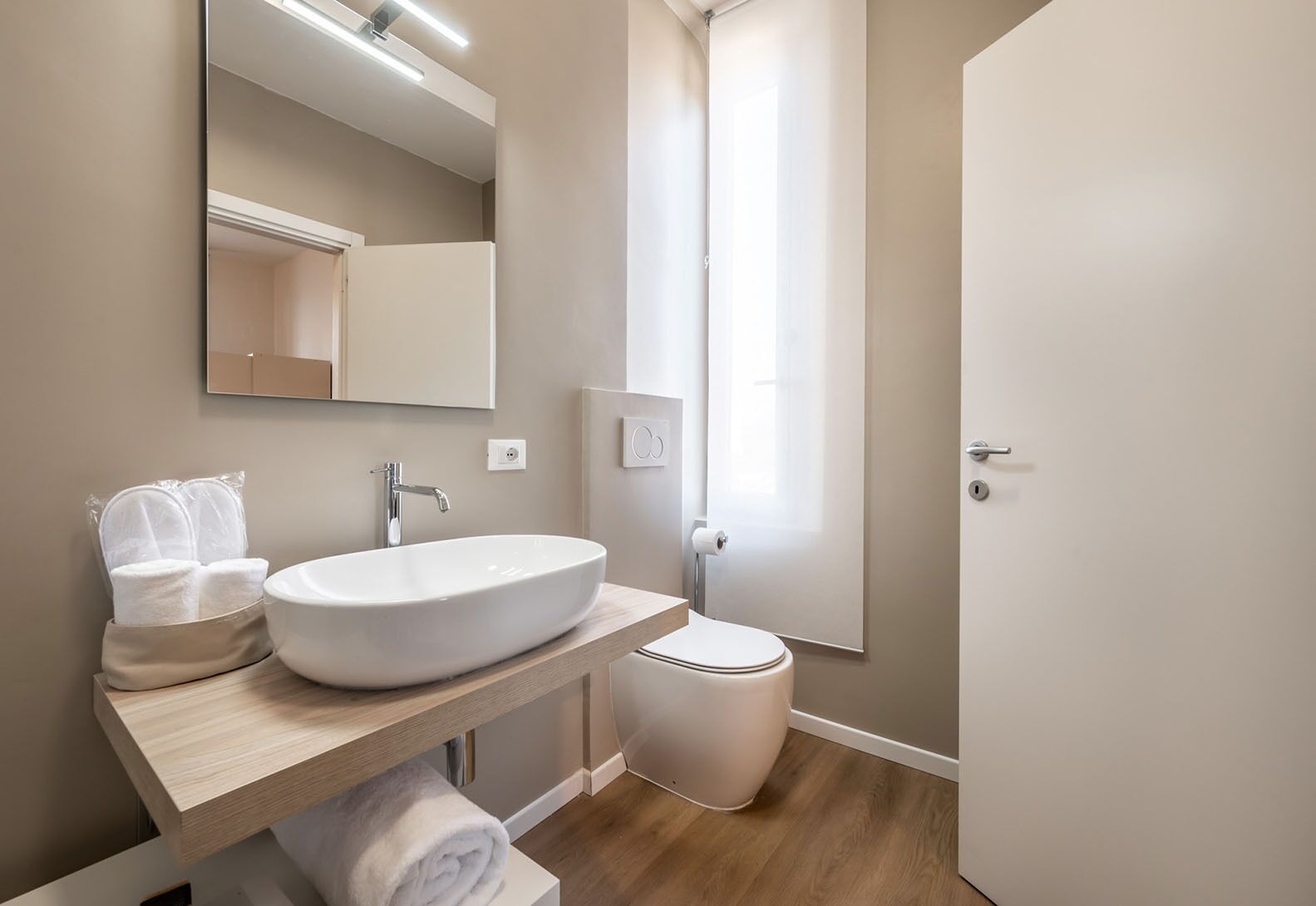 A modern bathroom with a large white sink, a mirror, and a toilet.
