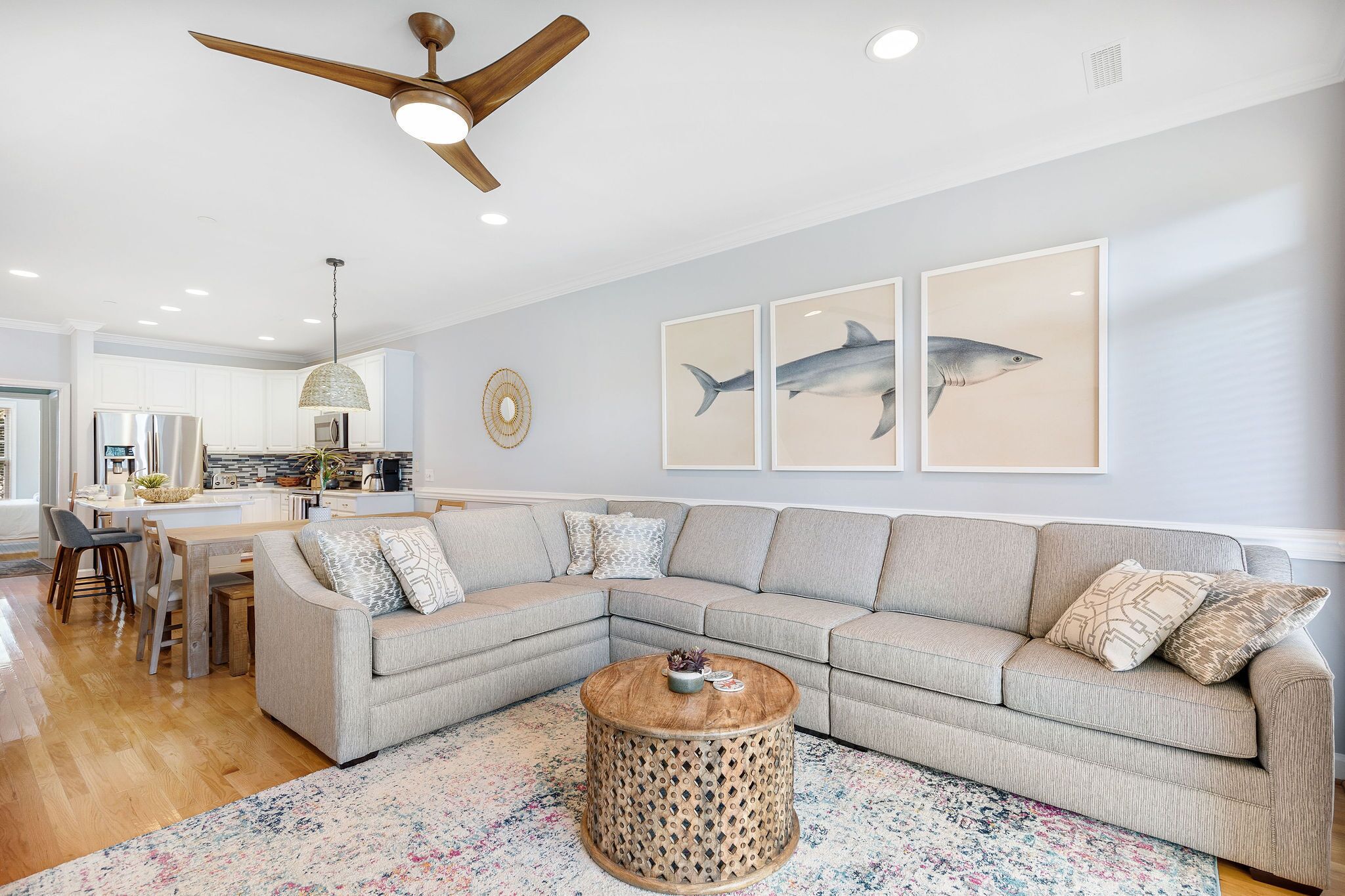 A modern living room with a sectional sofa, a round coffee table, and a ceiling fan.