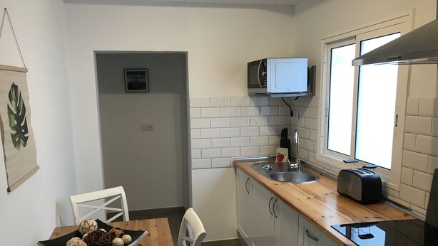 Une cuisine de taille réduite, avec une table en bois, un four à micro-ondes, un grille-pain et un évier.