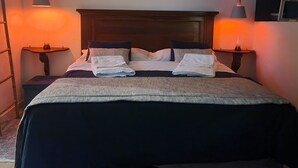 A neatly made bed with a dark headboard, two bedside tables with lamps, and framed pictures on the walls. - Il Rifugio (Palermo)