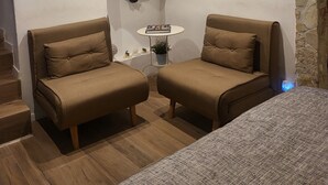 A cozy room with two brown armchairs, a small table with a plant, and a television on a shelf. - Il Rifugio (Palermo)