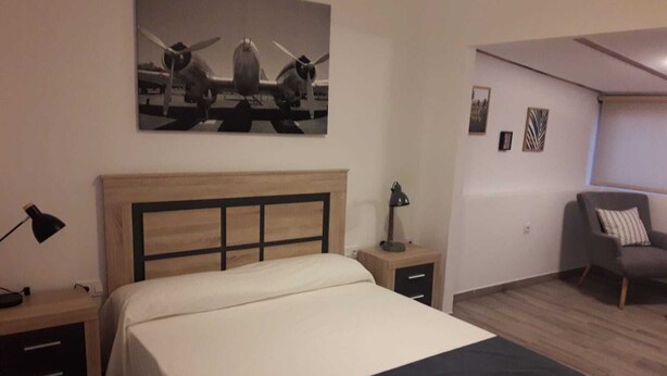 Un dormitorio con cama, mesitas de noche, escritorio y una silla.