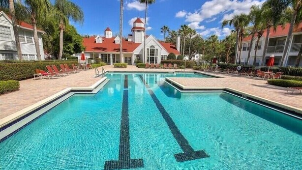 Una piscina con agua cristalina azul, rodeada de sillas de descanso y palmeras.