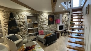 A modern living room with a stone wall, a sofa, a coffee table, and a staircase. - Cozy duplex apartment on the quays of Sète (Sète)