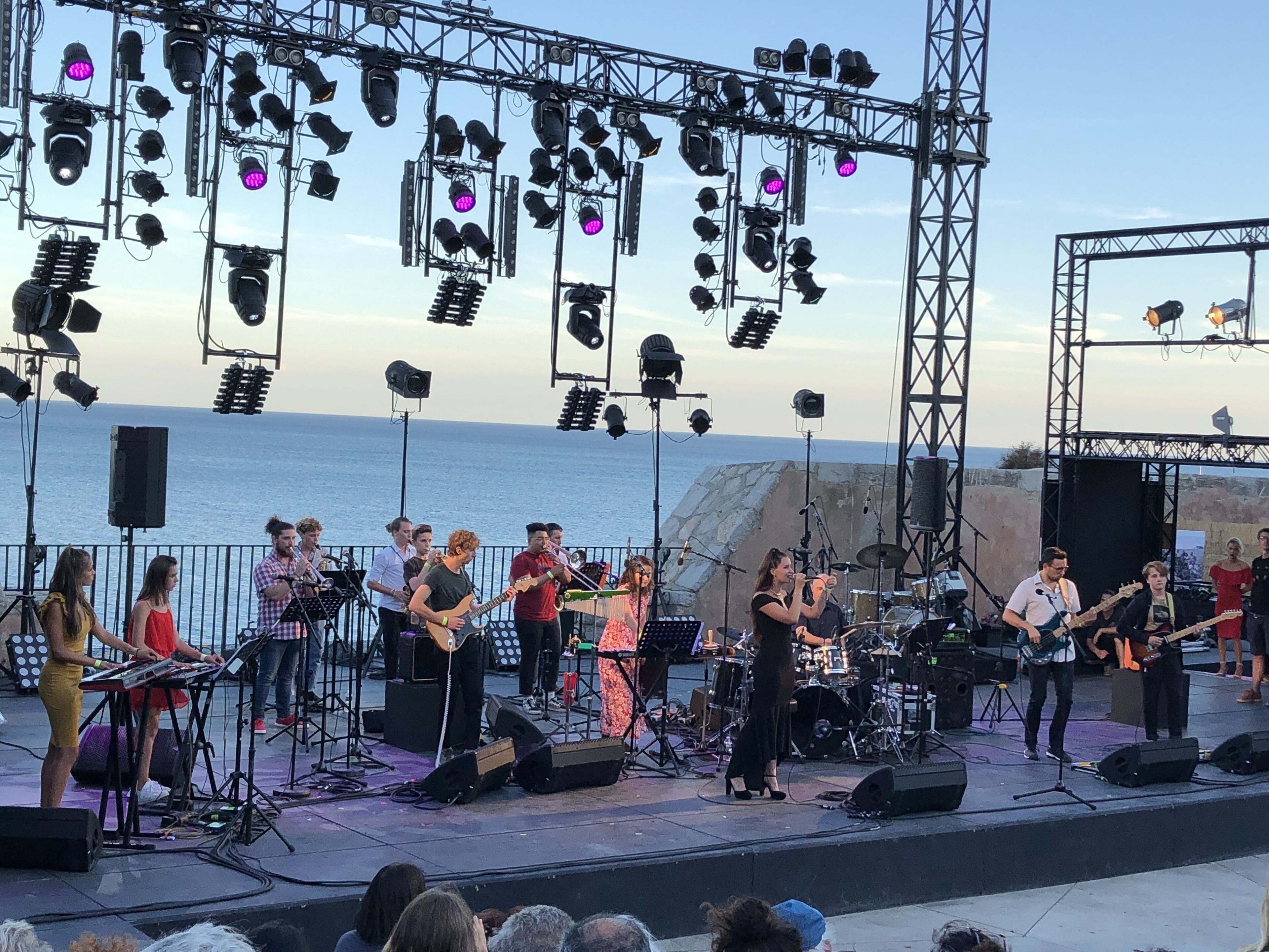 Un escenario con músicos actuando, equipado con varios instrumentos musicales e iluminación.
