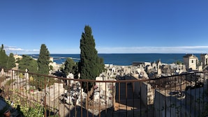 A cemetery with headstones and crosses, surrounded by trees and buildings, with a clear blue sky and sea in the background. - Cozy duplex apartment on the quays of Sète (Sète)