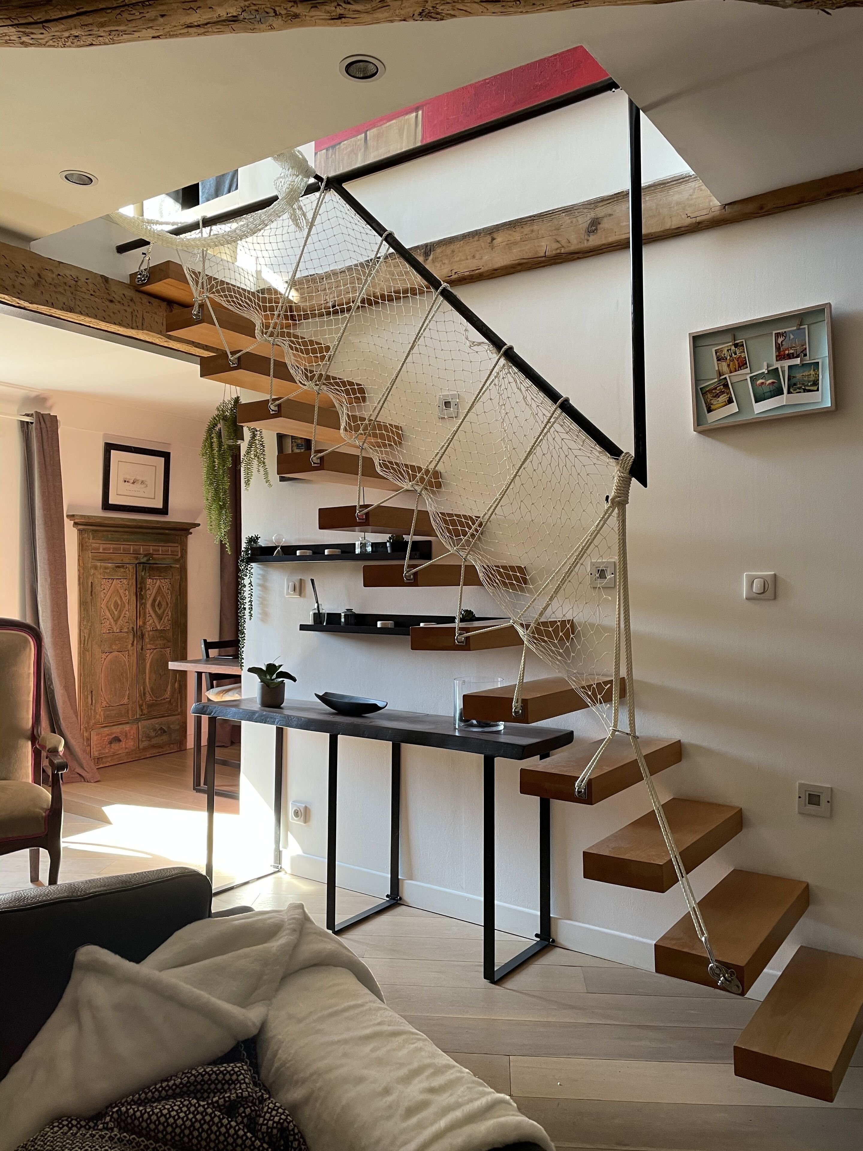 A modern staircase with a rope net, wooden steps, and a minimalist design.