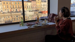 A person seated by a window overlooking a canal with buildings and boats. - Cozy duplex apartment on the quays of Sète (Sète)