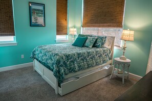 Une chambre à coucher avec un lit, deux lampes de chevet, une décoration en forme d’étoile de mer et un tableau encadré au mur.
