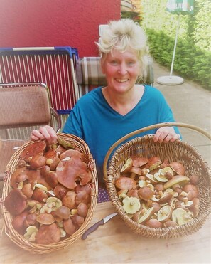 A person holding two wicker baskets filled with mushrooms.
