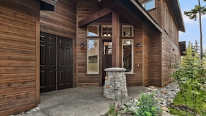 A wooden house with a stone entrance, large windows, and a gravel driveway. - Luxury Home in Suncadia! Great Value * Hot Tub * Specials! (Cle Elum)