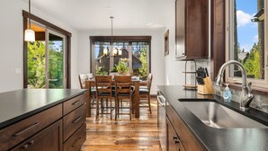 A modern kitchen with wooden cabinets, a black countertop, and a large window. - Luxury Home in Suncadia! Great Value * Hot Tub * Specials! (Cle Elum)