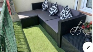 Un coin salon avec un banc rembourré, un vélo et une petite table agrémentée d’une plante.