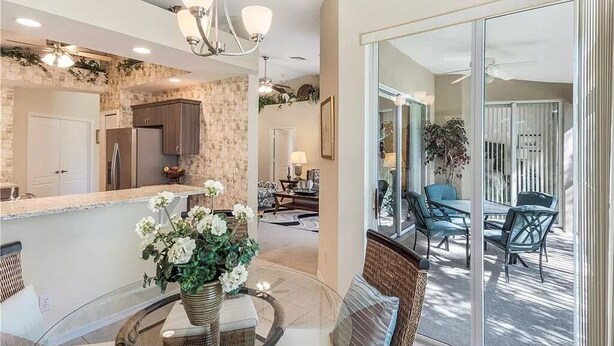 A modern kitchen with a stone backsplash, a dining area with a glass table, and a balcony with outdoor furniture.
