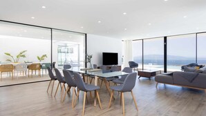 A modern living room with a glass dining table, grey chairs, a sofa, and a TV. - "New Home Costa Adeje, Luxurious Private Villa" (Costa Adeje)