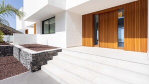 A modern building with a white exterior, stone steps, and wooden paneling. - "New Home Costa Adeje, Luxurious Private Villa" (Costa Adeje)
