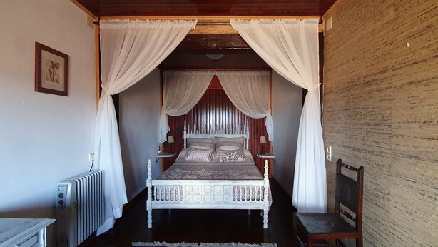 A room with a bed, a chair, a radiator, and a wooden wall.