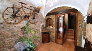 A rustic interior with a stone wall, a wooden door, and a bicycle hanging on the wall.