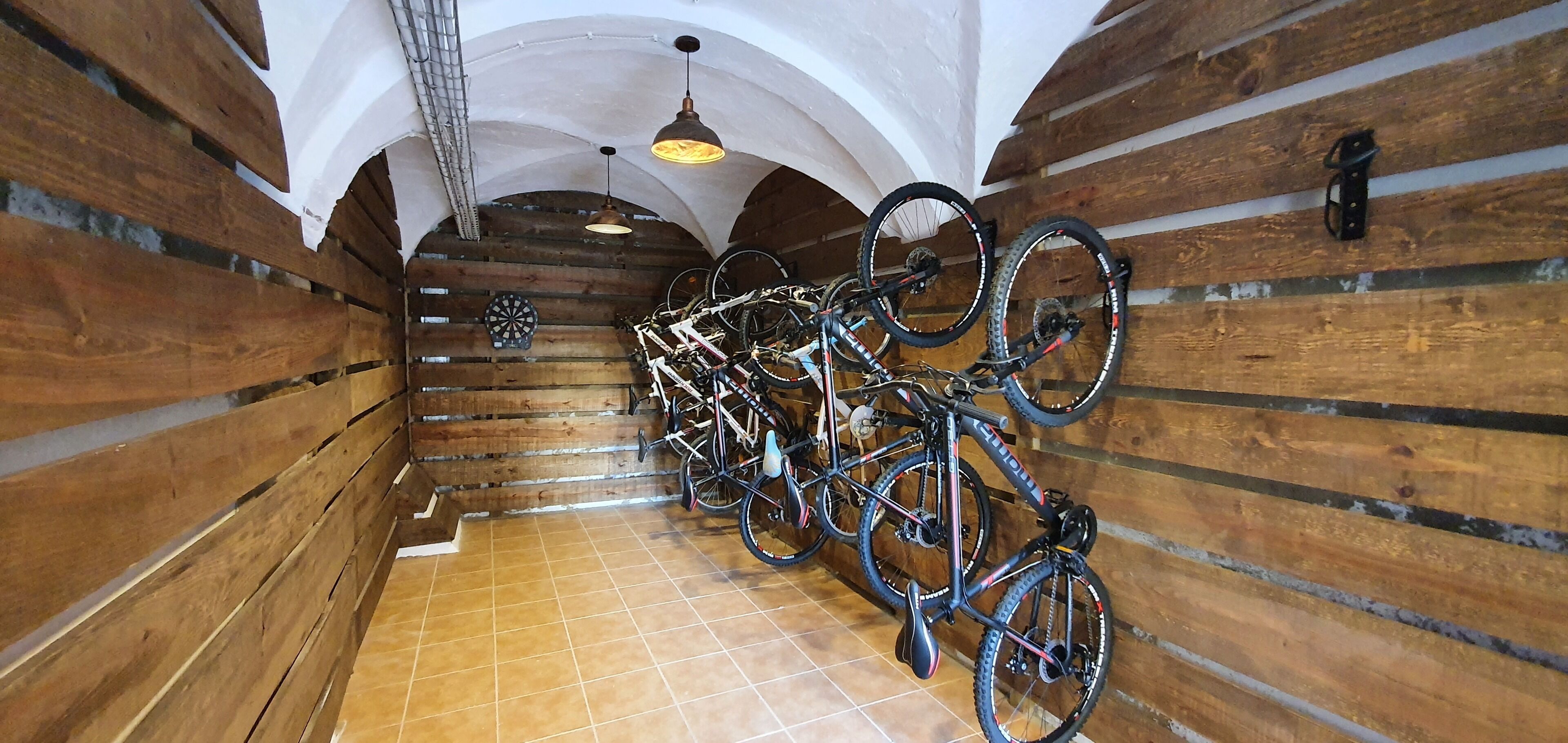 A narrow hallway with wooden walls and a tiled floor, lined with bicycles.