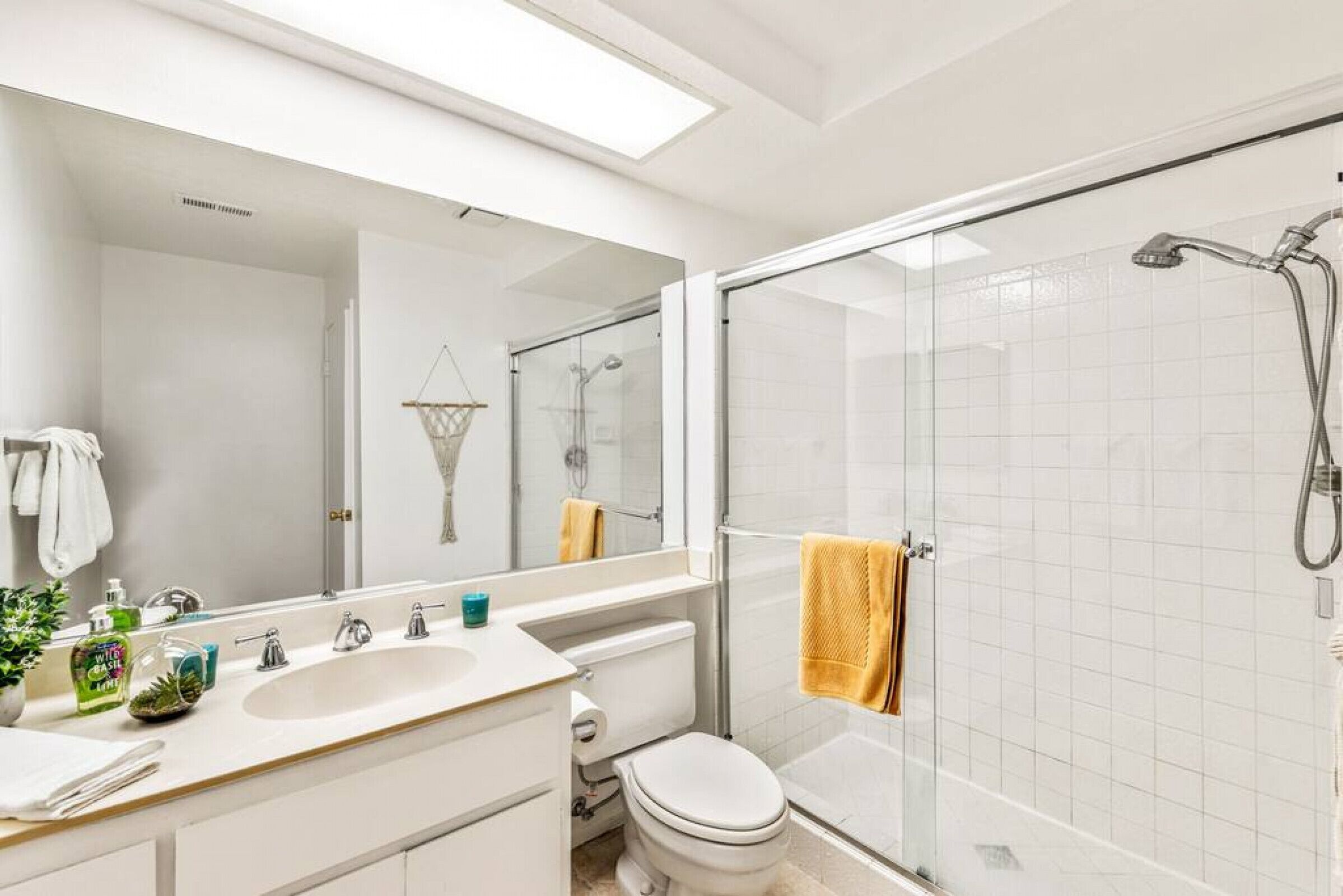 Ein modernes Badezimmer mit einer gläsernen Dusche, einem weißen Waschbecken und einer Toilette.